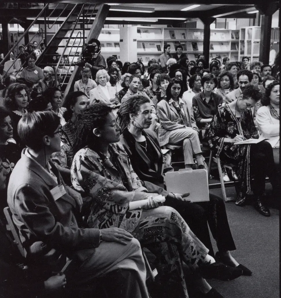 Zwart-wit foto van rijen mensen in de studiezaal die kijken naar Angela Davis die op de voorste rij zit
