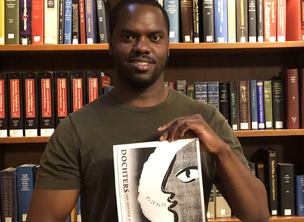 Man staat voor boekenkast en houdt een affiche in de handen