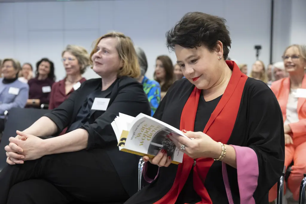 VNG-voorzitter en burgemeester van Utrecht Sharon Dijksma zit naast Atria-directeur Karin van der Heiden en bladert in het boek 'Ware wonderdieren', fotograaf: Henriëtte Guest.